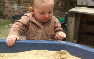Nursery child outside enjoying a sand based activity